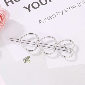 Close-up of silver hollow triple heart hair clip on a minimalist white card background
