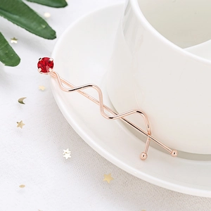 Elegante fermaglio per capelli ondulato oro rosa con una grande gemma rossa su piatto ceramico