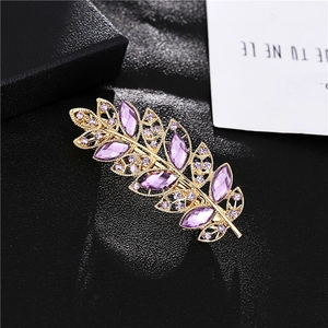 Elegant gold feather hair clip with purple marquise crystals on a black leather background