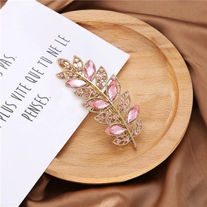 Elegant gold leaf hair clip with pink crystal rhinestones on a decorative satin background