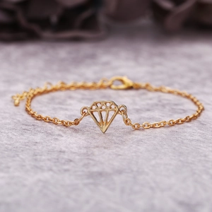 Gros plan détaillé d'un bracelet doré avec pendentif géométrique en forme de losange sur chaîne