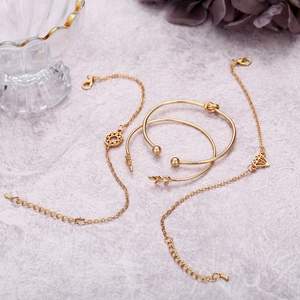Détail du lot de 4 bracelets dorés avec feuilles et motifs géométriques sur marbre
