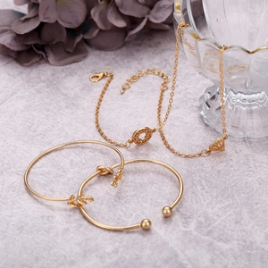 Vue détaillée d'un ensemble de quatre bracelets dorés à motif de feuilles sur marbre