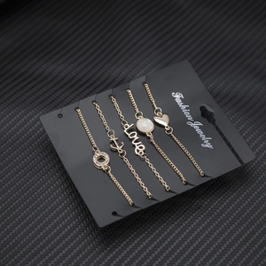 Dettaglio di un set di 5 bracciali dorati con ciondoli a cuore, ancora e scritta LOVE