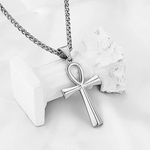 Polished silver Ankh cross pendant necklace with wheat chain on white decorative pillar