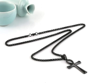 Macro detail of matte black Ankh cross pendant with textured wheat chain on white background
