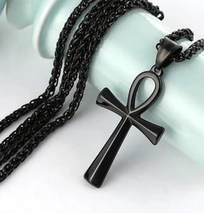 Close-up of black Ankh cross pendant with sturdy wheat chain on ceramic display