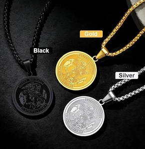 Saint Michael medal pendants in black, gold, and silver steel displayed on a rock