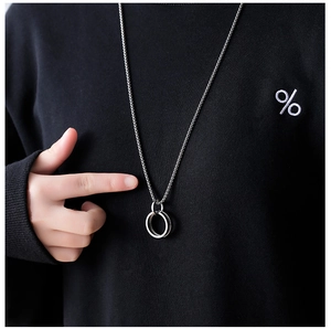Close-up of double-ring titanium steel necklace pendant worn on a black hoodie