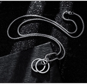 Detail of interlocking double ring pendant on box chain with sleek titanium steel finish