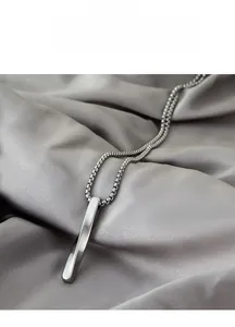 Macro view of a twisted rectangular pendant on a Venetian chain over grey silk