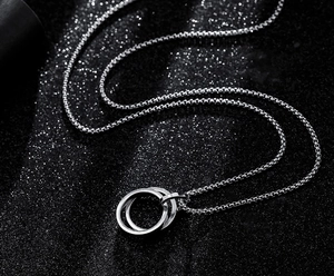 Close-up of interlocking silver rings on a sleek box chain against a dark backdrop