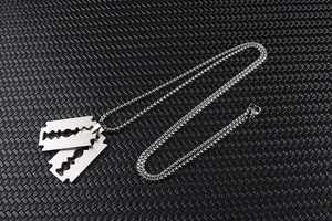Close-up of dual silver razor blade pendants on a stainless steel bead chain necklace