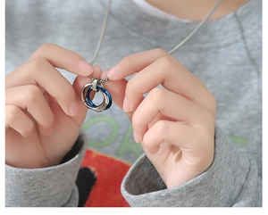 Détail du pendentif triple anneau entrelacé argent et bleu sur collier à billes
