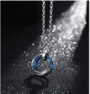 Détail macro du collier à trois anneaux imbriqués avec finition industrielle bleu et argent