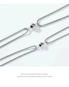 Detail of magnetic heart-shaped clasp connecting two stainless steel astronaut necklaces