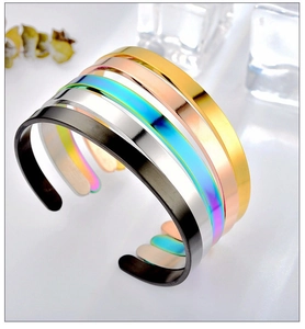 Stack of minimalist C-shaped stainless steel cuffs in five metallic colors on ice