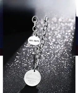 Détail macro du collier en acier inoxydable avec pendentifs gravés BELIEVE et LOVE TODAY
