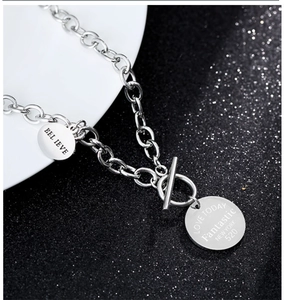 Détail du collier en acier argenté montrant le fermoir OT et les pendentifs gravés