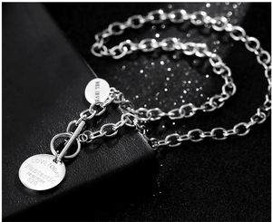 Gros plan d'un collier en acier inoxydable avec fermoir à bascule et pendentifs gravés