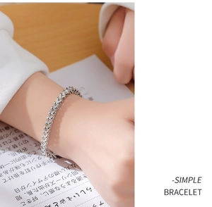 Detail of minimalist titanium steel wheat chain bracelet on wrist with silver finish
