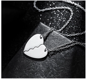 Macro shot of polished stainless steel heart puzzle necklace set for couples on black stand