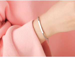 Detailed close-up of a silver-toned polished bar bracelet with a modern box chain link