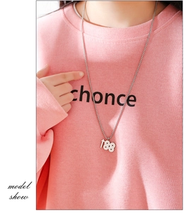 Vue macro du collier argenté avec pendentif 188 et chaîne fine sur un sweat rose