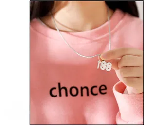 Détail du collier à pendentif 188 argenté sur un sweat à capuche rose style hip-hop