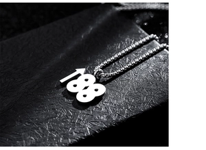 Macro du pendentif flèche 188 avec chaîne box en acier inoxydable sur surface noire texturée