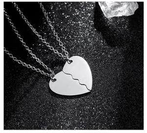 Close-up of interlocking heart puzzle necklaces in polished stainless steel on black glitter