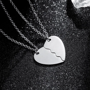 Polished stainless steel heart puzzle necklace for couples on black textured background
