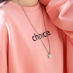 Collier hip hop avec pendentif 188 argenté porté sur un pull en maille rose