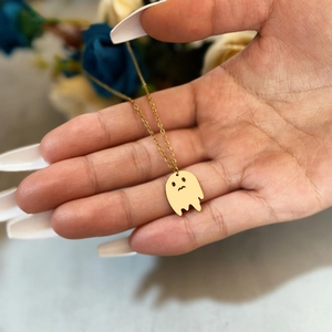 Close-up of a minimalist gold ghost pendant necklace with a polished finish for Halloween