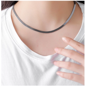 Close-up of a silver herringbone snake chain necklace on a model wearing a white tee