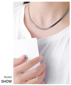 Detailed close-up of a silver herringbone snake chain necklace on a male model