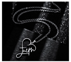 Macro shot of silver heart pendant with Faith script on black textured jewelry box
