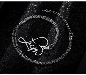 Detail of silver faith heart pendant necklace on black textured background with lobster clasp