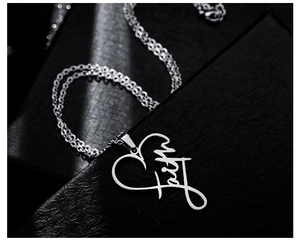 Detailed close-up of faith script pendant in heart-shaped stainless steel necklace