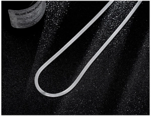 Flat silver snake chain necklace close-up on black glitter fabric with high metallic shine
