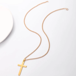 Detail of a minimalist gold cross pendant with fine link chain on a white background