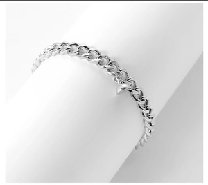 Detailed macro shot of silver stainless steel Cuban chain bracelet with heart-shaped charm