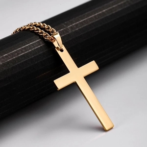 Polished gold stainless steel cross pendant necklace hanging on a textured black stand