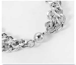 Close-up of a polished stainless steel Cuban chain with a magnetic ball clasp for couples