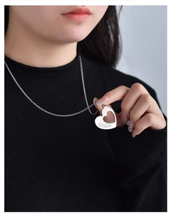 Détail du collier coeur en acier inoxydable argenté avec gravure Mother sur un pull