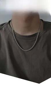 Détail d'un collier chaîne en acier titane argenté porté au cou d'un mannequin