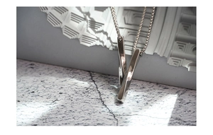 Macro view of geometric spiral pendant with Venetian chain on a stone texture background