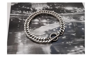 Close-up of silver Cuban link bracelet featuring a toggle clasp and polished metal finish