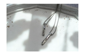 Macro shot of silver-tone twisted pillar pendants with fine box chains on a white plate