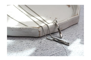 Macro view of twin spiral geometric bar pendants on chains with soft shadow background